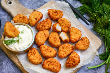 Crispy  deep fried   chicken  popcorn  nuggets and french fries . Breaded  with Cornflakes chicken  Breast fillets  with chilly peppers and fresh   basil on wooden rustic background