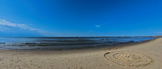 A vast sandy sea beach. Sunset over the sea. Beautiful sunny weather over the sea on a summer afternoon.
