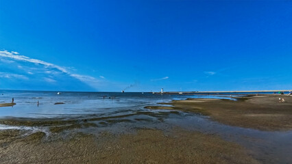 A vast sandy sea beach. Sunset over the sea. Beautiful sunny weather over the sea on a summer afternoon.