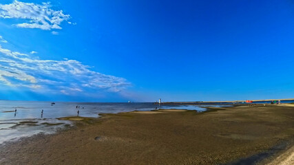 A vast sandy sea beach. Sunset over the sea. Beautiful sunny weather over the sea on a summer afternoon.