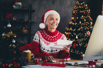 Photo of nice aged woman read letter use computer wear sweater christmas festive holiday apartment indoors