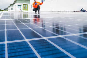 A worker in an orange safety jacket inspects solar panels on a rooftop, using a laptop to ensure...