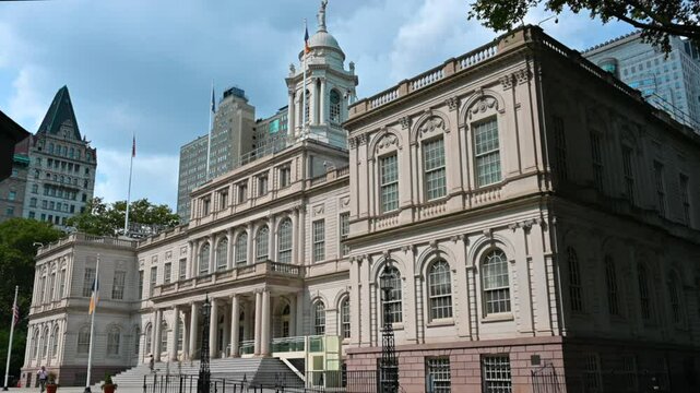 New York, USA, August 15, 2024. Nice static shot of the facade of the city hall seen from three-quarters, people can be seen coming out. Beautiful summer day. Travel destinations.