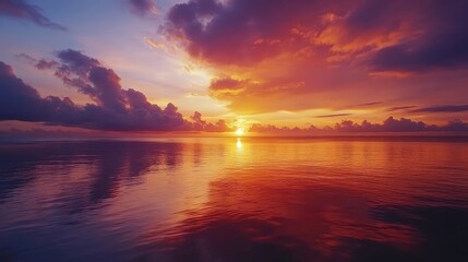 Fiery clouds reflecting the colors of a sunset above the horizon, creating a dramatic scene over the ocean