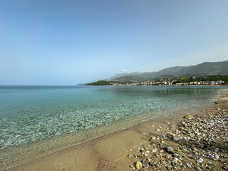 Panoramic view of the picturesque coastline of coastal tourist town Himare, Vlore, Albania. Idyllic sand beach Potami with scenic vistas of majestic Ceraunian mountains. Summer vacation concept