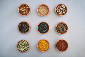 Spices, bowl and variety of herbs seasoning on studio background for cooking and top view mockup. Selection, organic condiments and flavor ingredients with cinnamon, masala powder and ground pepper