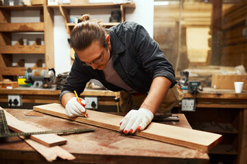 Man, building and pencil to measure wood at workshop, carpenter and tool for precision design. Male person, desk and manufacturing furniture with equipment, creative and check plank for construction