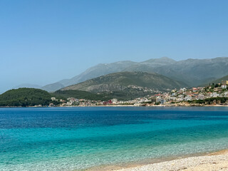 Panoramic view of the picturesque coastline of coastal tourist town Himare, Vlore, Albania. Sand beach Potami with scenic vistas of majestic mountains of Karaburun-Sazan Marine Park. Summer vacation