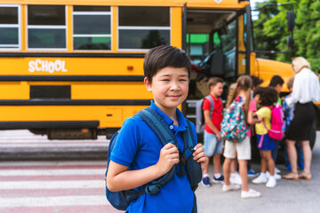 Group of young students attending primary school on a yellow school bus