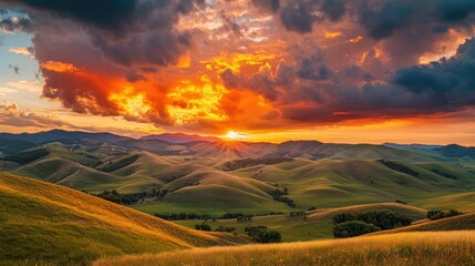 Fototapeta premium Majestic sunset behind rolling hills, clouds painted in fiery red and gold