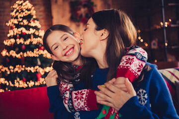 Photo of two peaceful people mother daughter embrace kiss new year xmas tree lights apartment...