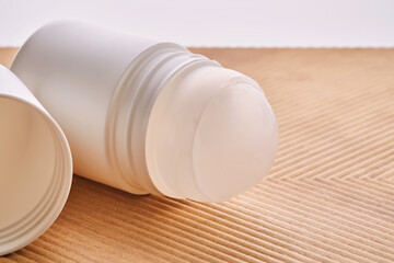 Roll-on deodorant on a background with beige grooves.