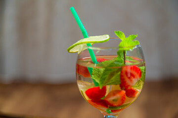 Non-alcoholic cocktail strawberry kiwi lime and mint in a glass on a wooden table