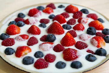 In a plate with whipped cream, fresh berries strawberries, raspberries and blueberries