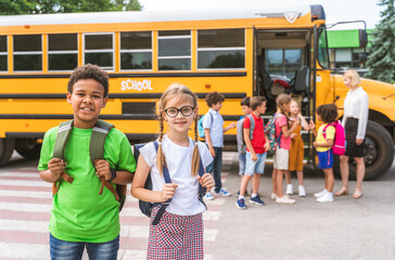 Group of young students attending primary school on a yellow school bus