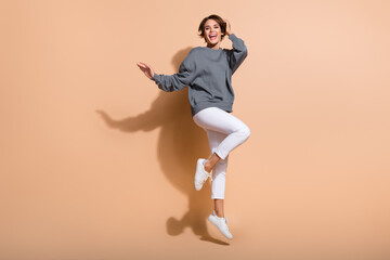 Full length photo of adorable girl wear oversize pullover white trousers flying hold palm on hair isolated on pastel color background