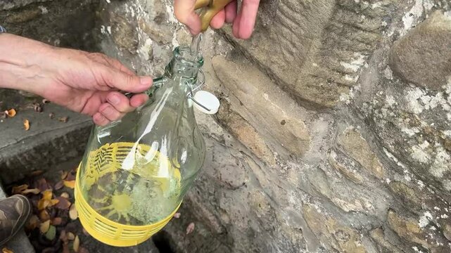 Raccolta dell'acqua in bottiglie di vetro