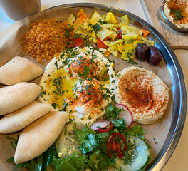 healthy breakfast with hummus, israeli cuisine. Scrambled eggs, hummus, salad, flatbread on a plate. Fast food prices rising, food shortages, giving up meat