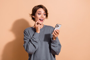 Photo of astonished woman with short hairdo dressed grey pullover look at 5g internet on smartphone...
