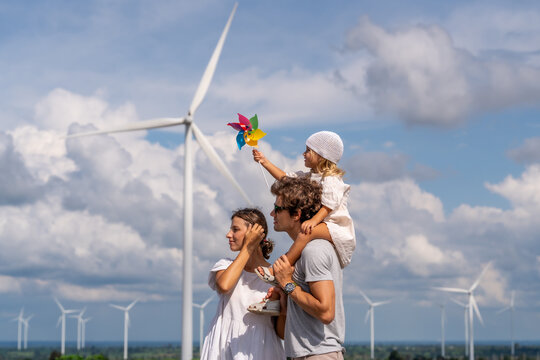 Family Enjoying Clean Energy with Wind Turbines in the Background on a Sunny Day