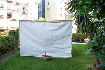 Jewish festival of Sukkot in Israel. Traditional sukkah with handmade decorations near the building on the street. 
