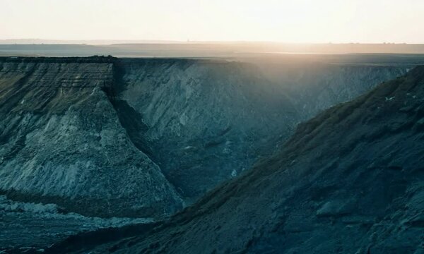 Pan shot with cool, early morning tones: The camera starts with a close-up of a tectonic plate boundary. It then pans across the boundary with cool, early morning tones highlighting the geological fea