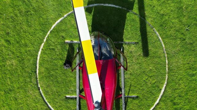 helicopter parked heliport green grass field london vibrant colors operational aspects close up top down birdseye aerial shot view forward drone helipad aviation 