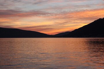 Colorful seascape sunset over Dark Mountain Landscape with Calm Waters. Sea background for publication, poster, screensaver, wallpaper, banner, cover, post. High quality photography