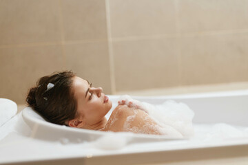 Relaxed woman enjoying bubble bath at home, with soft lighting creating a peaceful atmosphere....