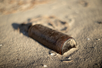 The shoreline after the tide receded revealed bottles, cans, and shells scattered on the stumps of...
