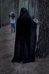 a dangerous human figure watches another in the forest to attack him - Halloween theme