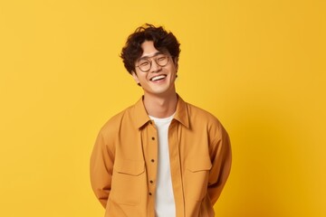Cheerful young man in yellow shirt and eyeglasses laughing