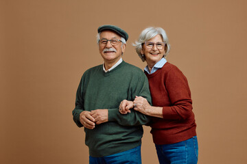 Portrait of happy senior couple on neutral background looking at camera.