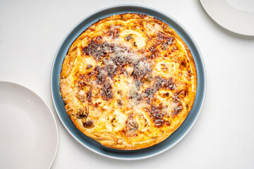 Traditional French pie. Quiche Lauren on a white kitchen table on a blue plate.