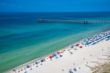 When the weather is nice, people gathering on Panama Beach City, Florida. The city is famous for its calm, clear and warm water. Background of umbrellas, waves, tiny people on different blue colors