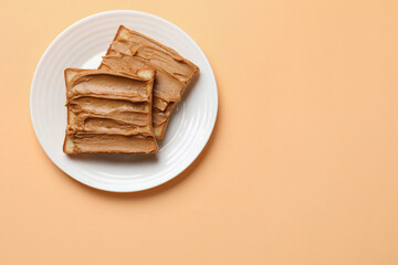 Delicious sandwiches with peanut butter on pale orange table, top view. Space for text