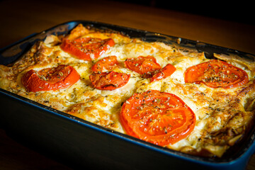 Traditional Italian lasagne dish with slices of tomatoes and melted cheese and crispy top