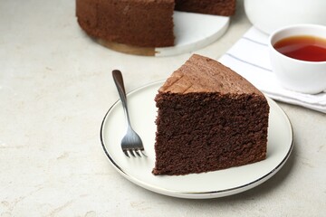 Piece of tasty chocolate sponge cake served on light table, closeup