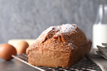Tasty sponge cake with powdered sugar on grey table, closeup