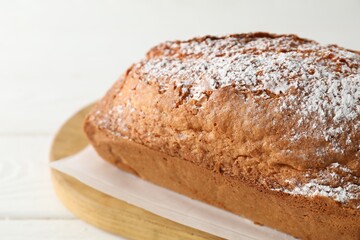 Tasty sponge cake with powdered sugar on white table, closeup