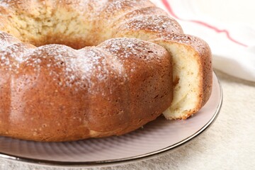 Freshly baked sponge cake on white textured table, closeup