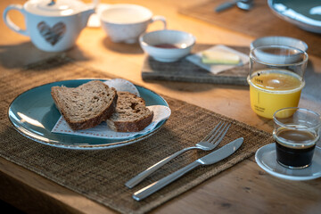 Lovingly prepared breakfast with bread, butter, coffee and orange juice on a blue plate and cups with a heart motif.