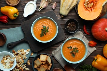 Delicious pumpkin soup and products on wooden table, flat lay