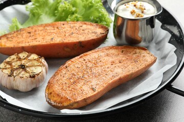 Tasty cooked sweet potato served in baking dish on grey table, closeup
