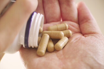 A man taking Resveratrol capsules out of a bottle. Close up.