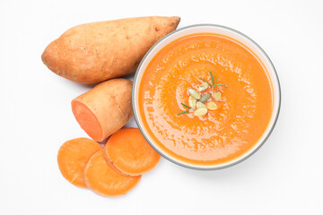 Delicious sweet potato soup with pumpkin seeds in bowl and fresh vegetables isolated on white, top view