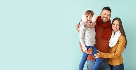 Happy family in winter clothes on light blue background with space for text