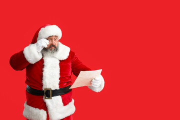 Shocked Santa Claus reading letter on red background