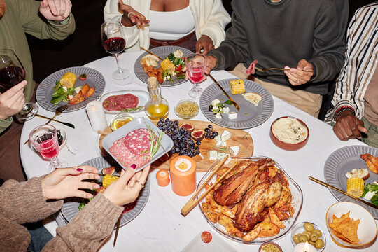 Vibrant top view of festive dinner table with unrecognizable people celebrating holidays together and enjoying meal, shot with flash