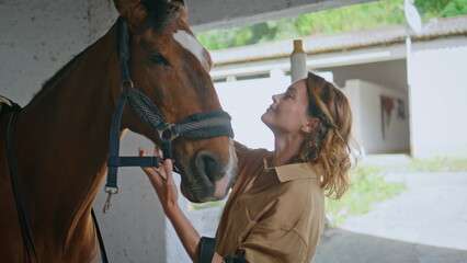 Joyful equestrienne petting horse serene barn closeup. Woman cuddling stallion